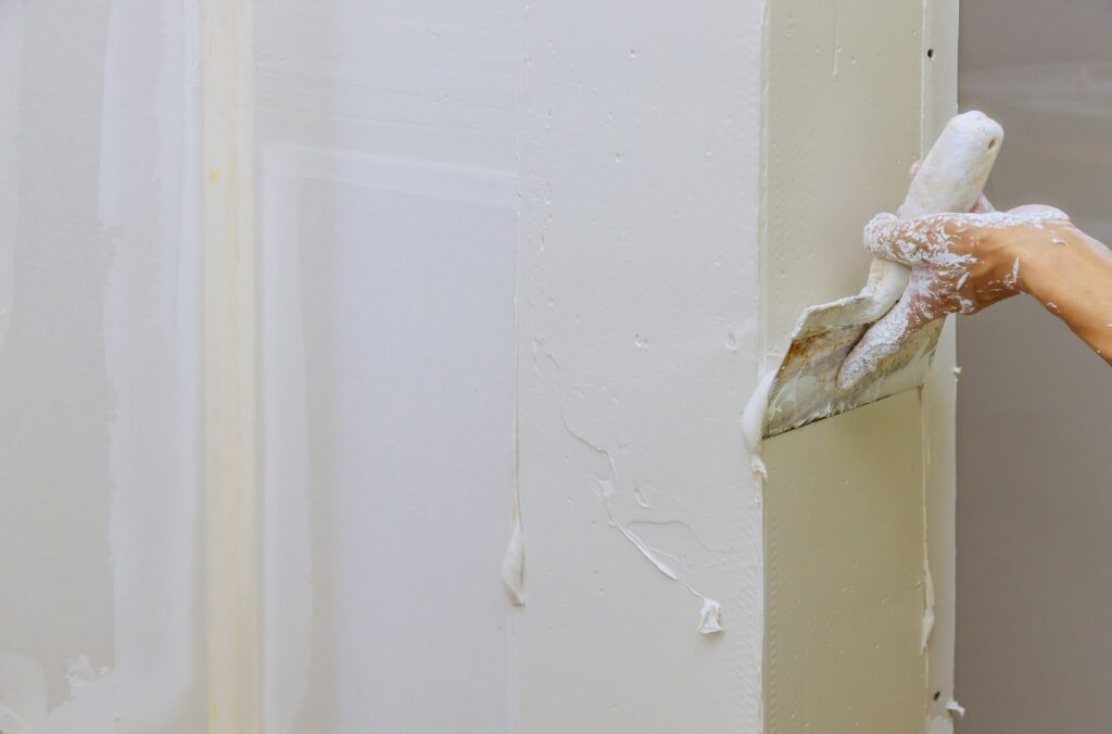 Hand of worker using gypsum plaster coating plaster walls construction